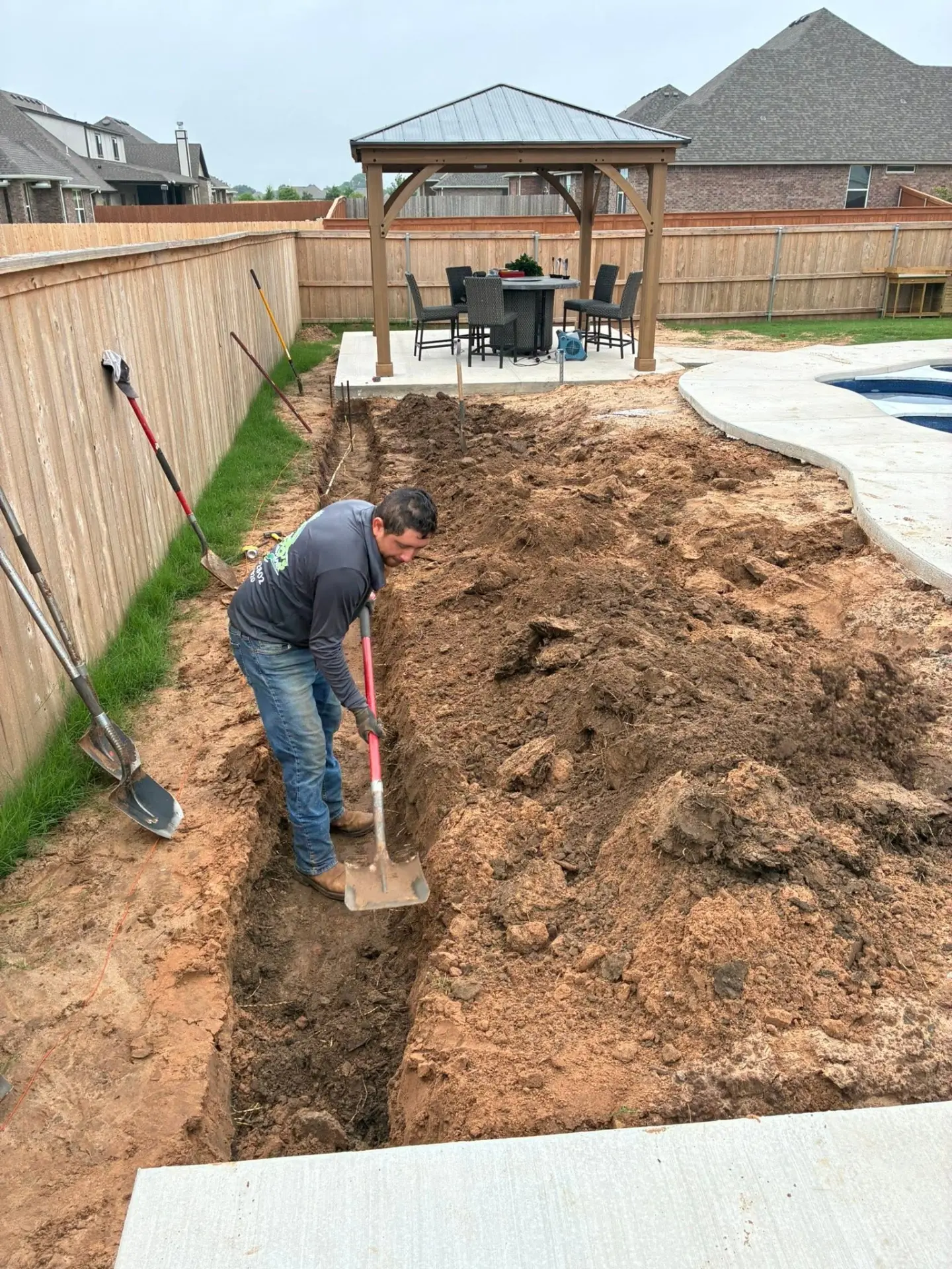 Fernando's Landscaping crew excavating a drainage trench on an Oklahoma City property